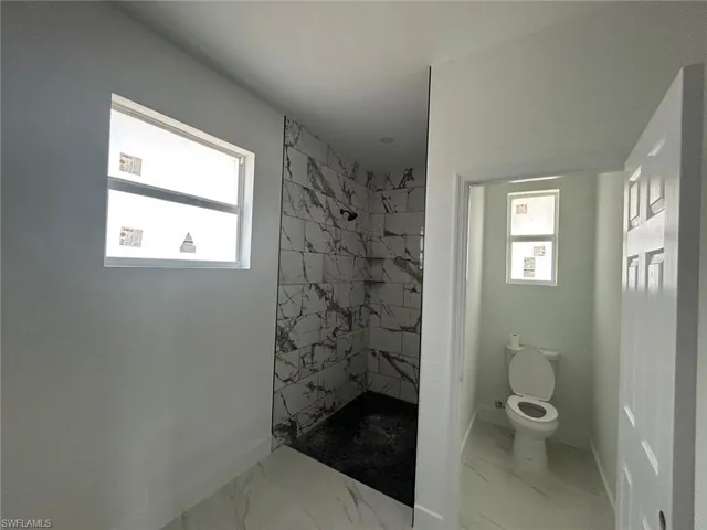 Full bathroom with marble finish flooring and a marble finish shower