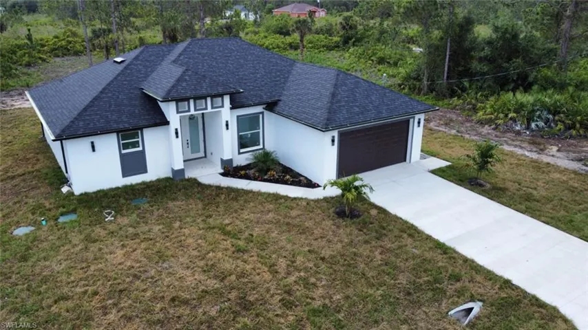 View of front facade featuring an attached garage, stucco siding, concrete driveway, and a front lawn