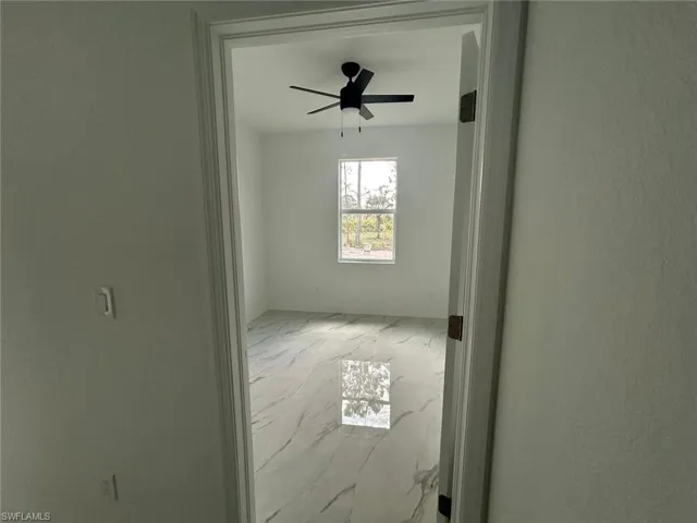 Spare room featuring marble look tile flooring and ceiling fan