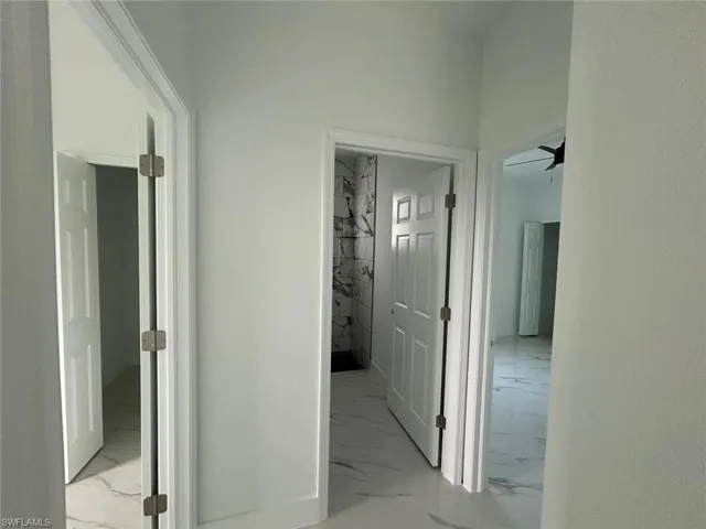 Hallway featuring light marble finish floors