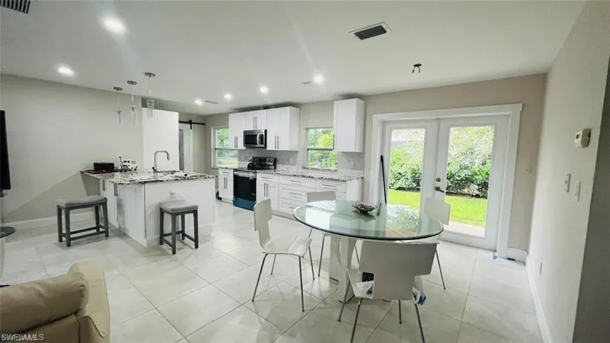 Dining area with french doors, recessed lighting, light tile patterned floors, and a barn door