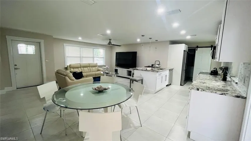 Dining space with a barn door, a ceiling fan, recessed lighting, and light tile patterned floors