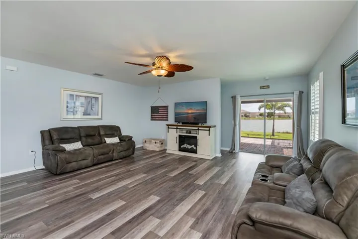 Living area featuring baseboards, wood-style flooring, ceiling fan, sliding glass to extended screened in lanai