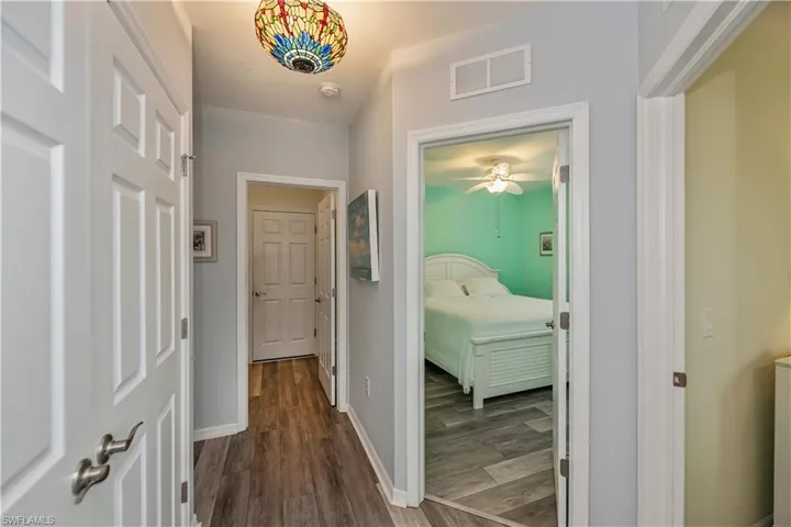Hallway with wood-style floors, visible vents, and baseboards