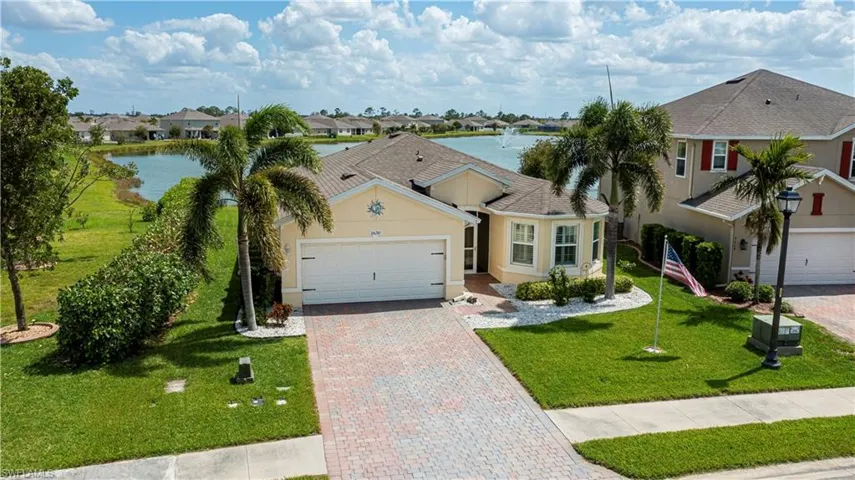 View of front of home with a water view, decorative driveway, a garage, a front yard, and stucco siding