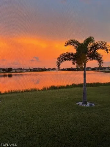 Picture taken from the lanai through the panoramic super screen. View of the sunsets and water views you will enjoy.  Notice the upgraded full and healthy lush lawn they replace their yard with.