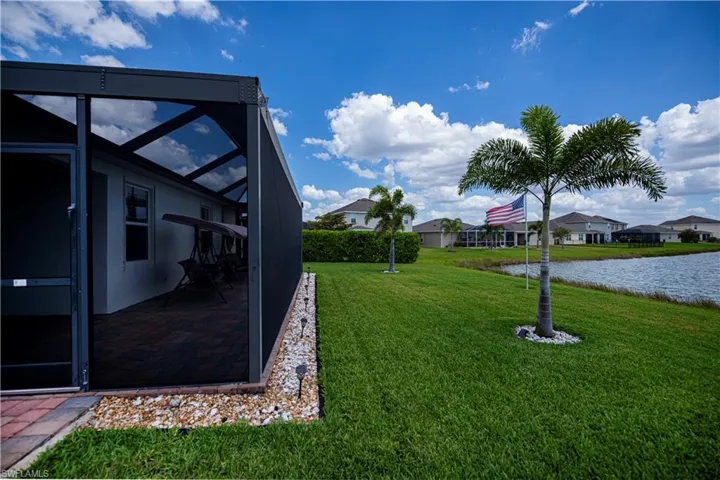 Back View of yard, curbing with mixed rocks, water view,  and screened in extended patio