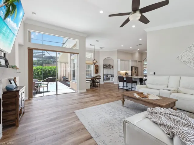 Living room featuring light wood-type flooring, ceiling fan, and ornamental molding