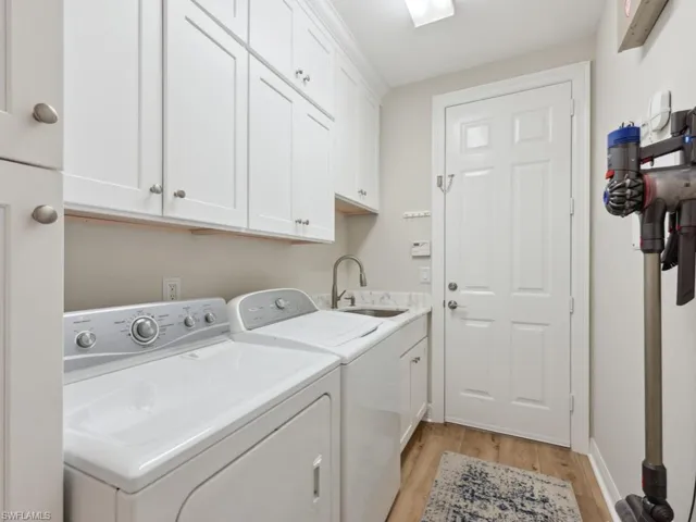 Laundry room with light hardwood / wood-style floors, sink, cabinets, and washing machine and dryer