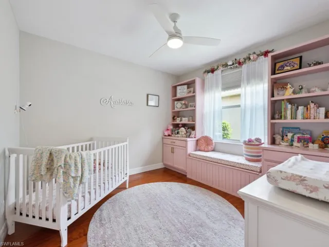 Bedroom featuring a crib, light hardwood / wood-style flooring, and ceiling fan