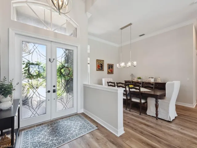 Foyer entrance with a notable chandelier, a healthy amount of sunlight, and hardwood / wood-style floors. View into formal dining room