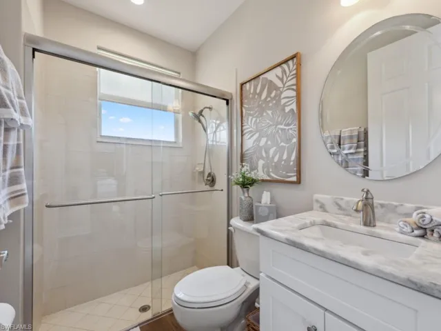 Bathroom with a shower with door, vanity, and toilet