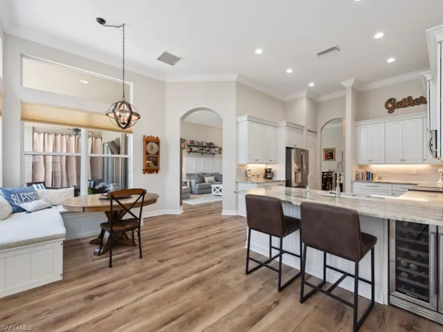 Kitchen featuring pendant lighting, light hardwood / wood-style floors, light stone countertops, stainless steel fridge with ice dispenser, and wine cooler