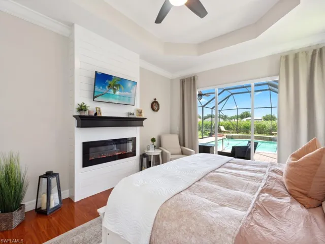 Bedroom featuring a tray ceiling, access to outside, ceiling fan, wood-type flooring, and ornamental molding