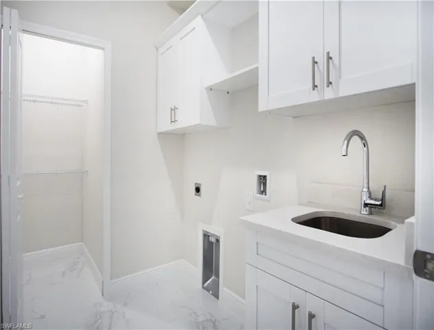 Washroom featuring hookup for a washing machine, sink, cabinets, hookup for an electric dryer, and light tile patterned flooring