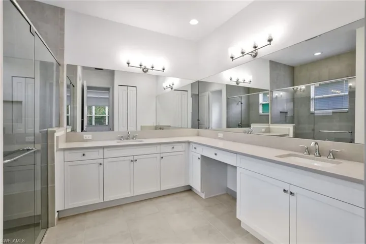 Master Bathroom featuring vanity with extensive cabinet space, walk in shower, double sink, and tile floors