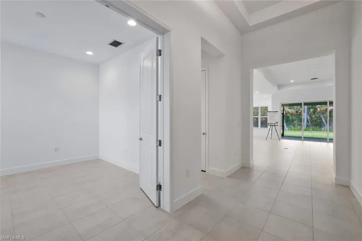 Hallway with a tray ceiling and light tile floors