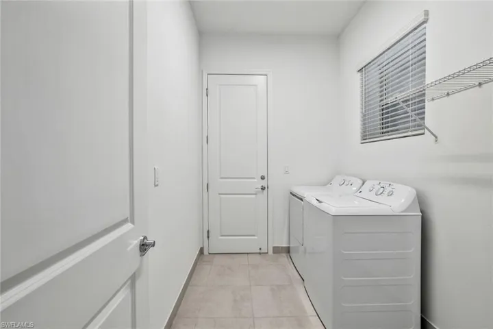 Laundry area featuring washing machine and dryer and light tile floors