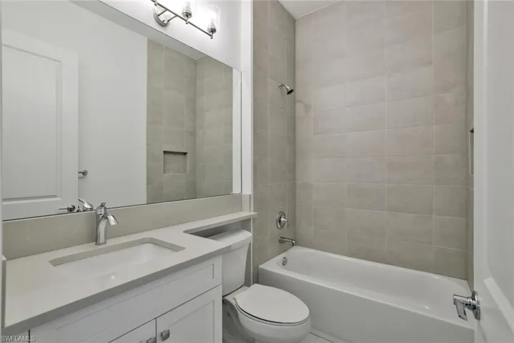 Full bathroom featuring tiled shower / bath, vanity, and toilet