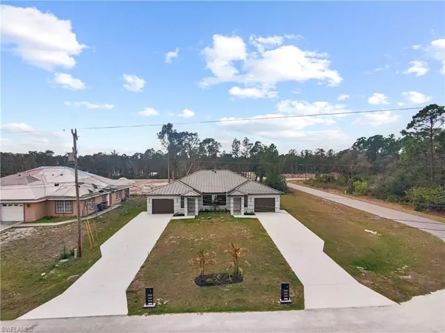 View of front of home with concrete driveway, a front lawn, a standing seam roof, and an attached garage