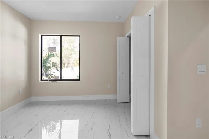 Unfurnished bedroom featuring light marble finish flooring and baseboards