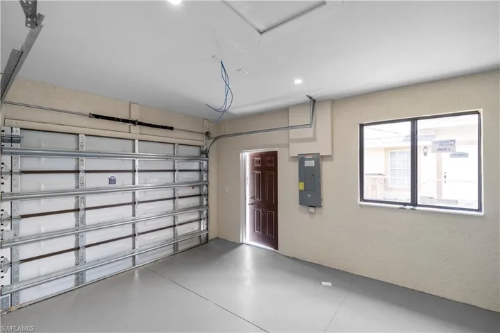 Garage with electric panel, recessed lighting, and a textured wall