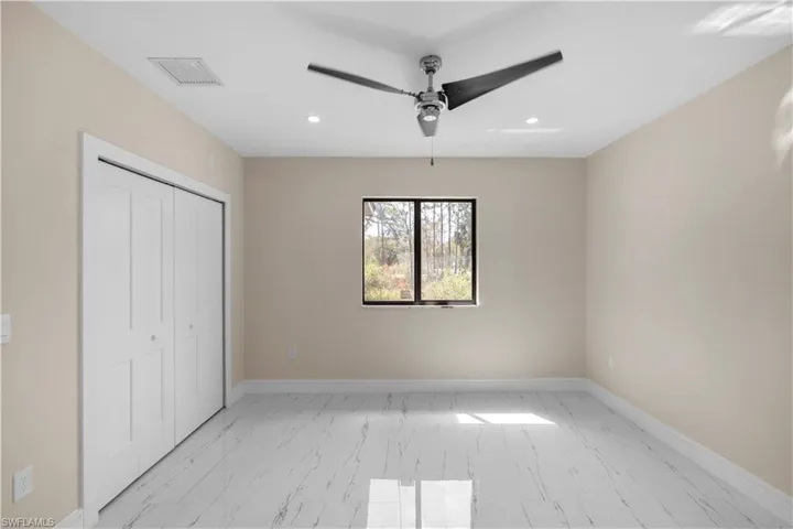 Unfurnished bedroom featuring a closet, recessed lighting, a ceiling fan, and light marble finish floors