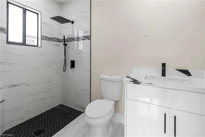 Bathroom featuring vanity and a marble finish shower