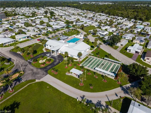 Community clubhouse with a swimming pool, multiple shuffleboard courts, and manicured green spaces