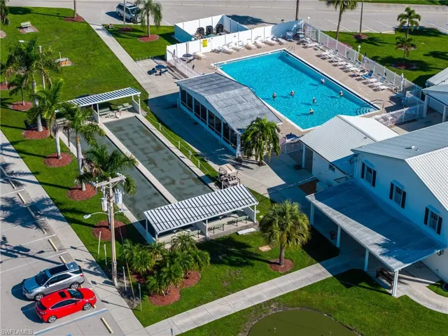Outdoor swimming pool with lounge seating, bocce ball court, covered picnic areas, and manicured landscaping