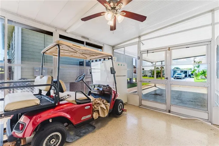 Enclosed patio featuring a ceiling fan, exposed aggregate flooring, and multiple screened panels