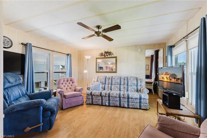 Wood-finish flooring, ceiling fan, and multiple windows with roller shades
