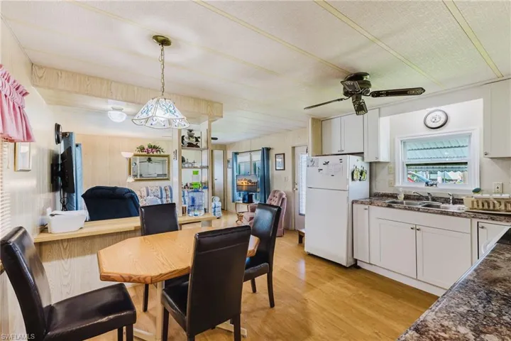 Kitchen and dining area featuring wood-finish flooring, white cabinetry, and a ceiling fan