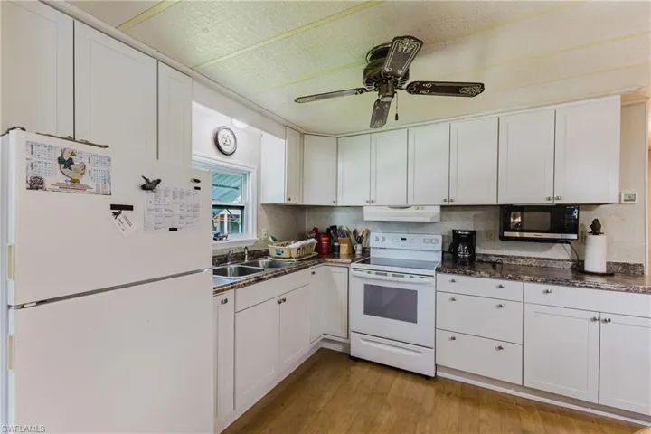 Kitchen featuring white cabinetry, wood-finish flooring, a ceiling fan, and built-in appliances