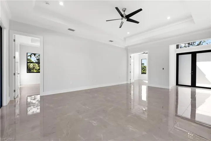 Living room featuring a raised ceiling, ceiling fan, light marble finish flooring, ornamental molding, and recessed lighting