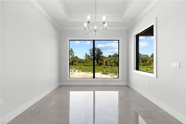 Unfurnished dining area with plenty of natural light, a chandelier, a tray ceiling, and ornamental molding