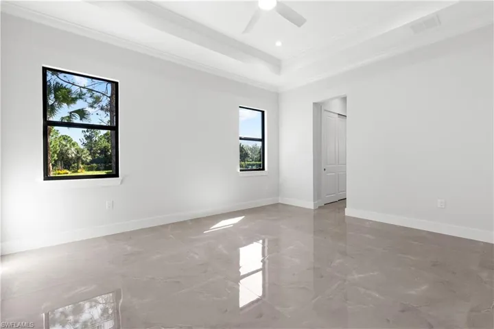 Empty room with crown molding, a raised ceiling, light marble finish flooring, ceiling fan, and recessed lighting