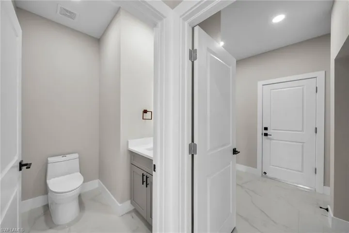 Half bath with light marble finish flooring, vanity, and recessed lighting