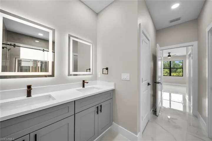 Bathroom with double vanity, a shower stall, recessed lighting, and a ceiling fan