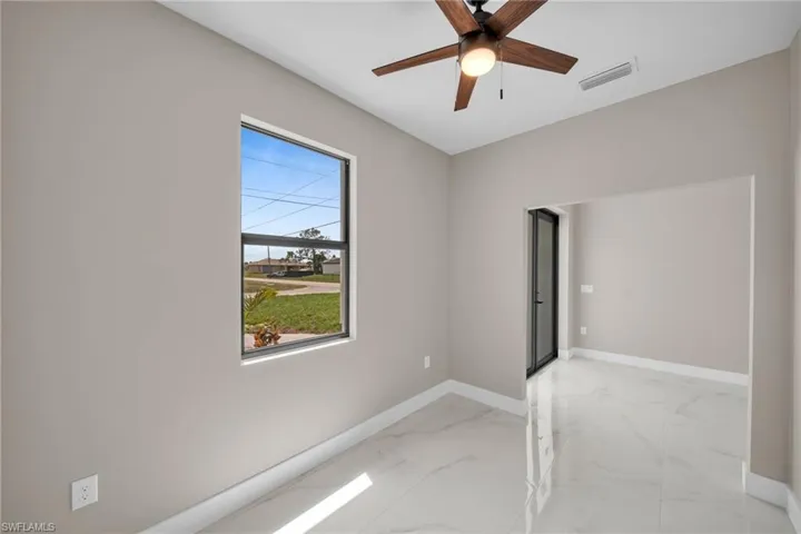 Spare room featuring light marble finish floors and ceiling fan