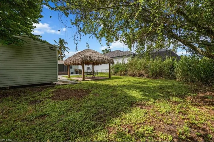 View of back yard featuring tiki hut and shed