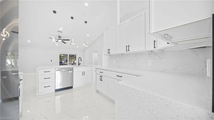 Kitchen featuring white cabinetry, light stone counters, appliances with stainless steel finishes, recessed lighting, and decorative light fixtures
