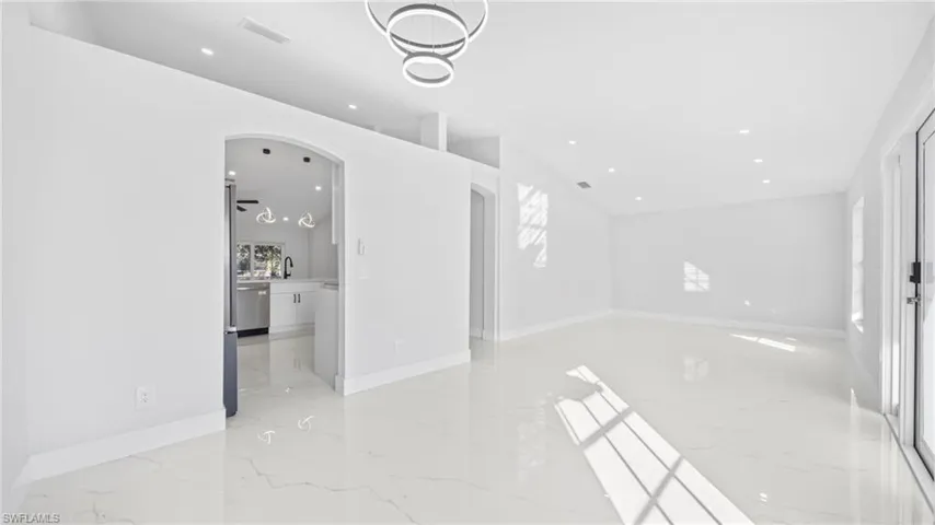 Unfurnished room featuring arched walkways, recessed lighting, and light marble finish flooring