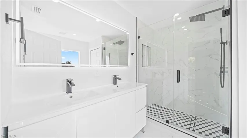 Full bathroom with double vanity, a marble finish shower, and recessed lighting