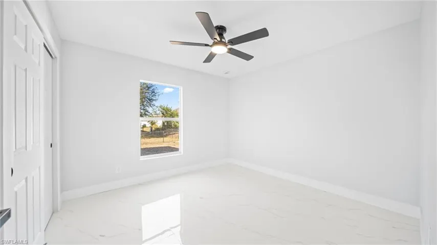 Unfurnished bedroom with light marble finish floors, a closet, and a ceiling fan