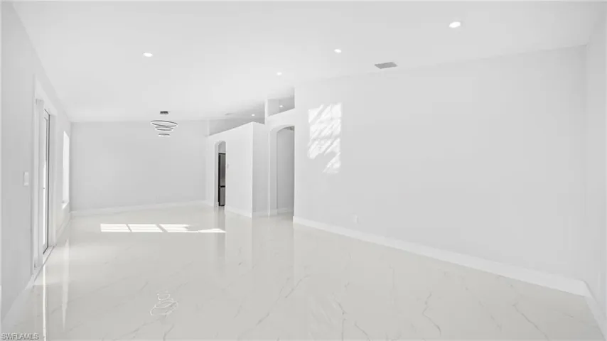 Spare room with arched walkways, recessed lighting, and light marble finish flooring