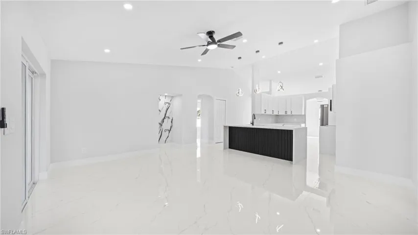 Unfurnished living room featuring arched walkways, recessed lighting, a ceiling fan, high vaulted ceiling, and light marble finish floors