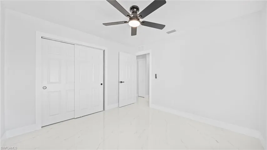 Unfurnished bedroom featuring a ceiling fan, a closet, and light marble finish floors