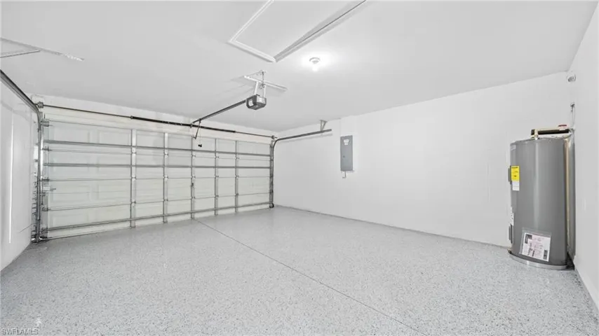 Garage with water heater, electric panel, and concrete block wall