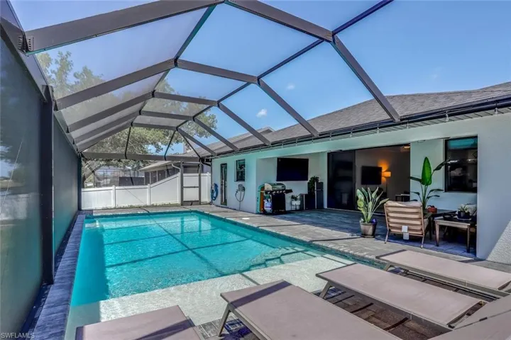 Screen-enclosed swimming pool featuring a paver deck